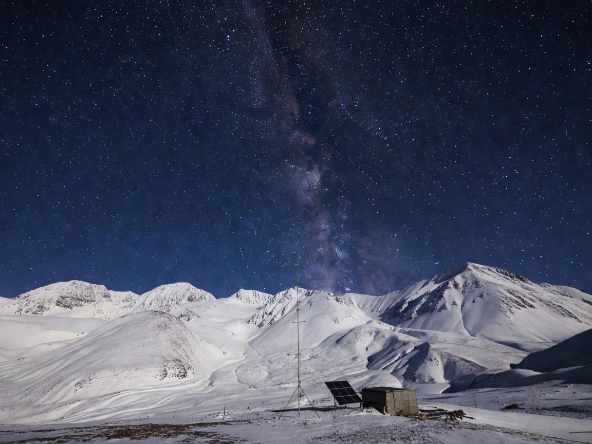 Starry night sky over snow-covered mountains representing off-grid communications